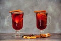 Two glass transparent glasses of hot red wine with orange and apple slices and spices stand on a wooden table Royalty Free Stock Photo