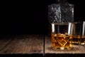 Two glass of whiskey with ice and crystal decanter on wooden table