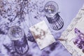 Two glasses and card note with iris flower on pastel lilac background with white cloth and shadows. Summer refreshment Royalty Free Stock Photo