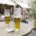 Two glasses of beer stand on a table in a street cafe with bills for payment, selective focus Royalty Free Stock Photo