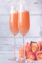 Two glasses of bellini cocktail with bouquet of roses