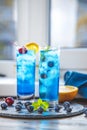 Two glasses of blue gin tonic cocktail with ice a mix of alcohol near the window on the table near window in the sun falltime. Royalty Free Stock Photo