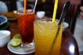 Two glasses of Cambodia style drinks. One is orange juice, the other is black tea.