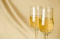 Two glasses of champagne on a background of a fabric of golden c