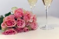 Two glasses of champagne and a bouquet made of beautiful light red / blush pink roses Royalty Free Stock Photo