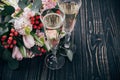 Two Glasses Of Champagne And Bouquet Of Pink Flowers On Dark Woo
