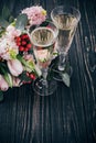 Two glasses of champagne and bouquet of pink flowers on dark woo Royalty Free Stock Photo