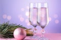 Two glasses of champagne, christmas ornaments, fir tree branch in pink and purple colors. Copy space, bokeh background Royalty Free Stock Photo