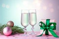 Two glasses of champagne, christmas ornaments, wrapped gift and fir tree branch in pink and mint colors. Copy space Royalty Free Stock Photo