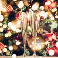 Two glasses of champagne with Christmas tree background and sparkles. Holiday season background. Traditional red and green Royalty Free Stock Photo