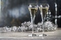 Two glasses of champagne on white wooden table with silver decorations.