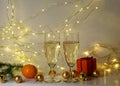 Two glasses of champagne, golden glass balls and various Christmas decorations, illuminated background of a chain of white lights Royalty Free Stock Photo