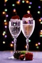 two glasses of champagne with an ornament in the form of a Santa Claus hat and a fir twig of a pine cone and a gift box