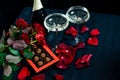 Two glasses of champagne, red roses, petals and chocolates on a black background Royalty Free Stock Photo