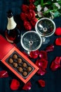 Two glasses of champagne, red roses, petals and chocolates on a black background Royalty Free Stock Photo