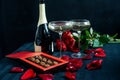 Two glasses of champagne, red roses, petals and chocolates on a black background Royalty Free Stock Photo