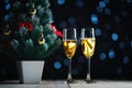 Two Glasses of Champagne and Small Christmas Tree Dark Glow Lights Background. Royalty Free Stock Photo