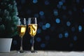 Two Glasses of Champagne and Small Christmas Tree Dark Glow Lights Background. Room For Text Royalty Free Stock Photo