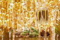 Two glasses of champagne and a spruce branch with cones on golden background of sparkling lights of garlands Royalty Free Stock Photo