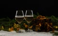 Two glasses of champagne stand in the snow against the background of fir branches, toys, gifts and garlands in Royalty Free Stock Photo