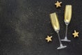 Two glasses of champagne toasting with golden glitter on a black background. Holiday background. Celebrate party concept.