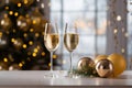 Two glasses of champagne on white table with gold color party ornament and balloons, with blurred Christmas tree on background, Royalty Free Stock Photo