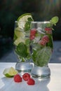 Two glasses of cocktail, classic Mojito and raspberry Mojito in the sun