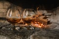 Two glasses of cognac, brandy stands near the fireplace with an open fire, sparks of flame