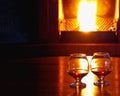 Two glasses of cognac on the old brick fireplace with bright fire Royalty Free Stock Photo