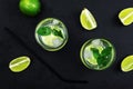 Two glasses of cold drink with lime slices and ice decorated with fresh mint leaves. Refreshing cold beverage. Black Royalty Free Stock Photo