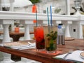 Two glasses of cold mojitos and an iced strawberry cocktail sit on a table on the cafe`s summer veranda. Glasses with a tube cover Royalty Free Stock Photo