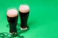 Two glasses of dark stout beer and traditional clover shaped decor