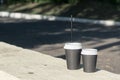 Two glasses, different in volume, black color stand on a concrete stand. One of the cups with a straw.