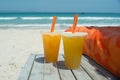 Two glasses of fresh orange juice on white sandy beach in front of sea Royalty Free Stock Photo