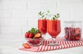 Two glasses of fresh strawberry smoothie and a bowl of ripe strawberries on a red striped napkin in the white kitchen Royalty Free Stock Photo