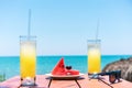 Two glasses of fresh tropical fruit juice on the beach, and a plate with grapes and watermelon on the table, against the sea. Royalty Free Stock Photo