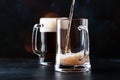 Two glasses of german light beer, beer poured into mug, dark bar counter background, selective focus Royalty Free Stock Photo