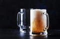 Two glasses of german light beer, beer poured into mug, dark bar counter, selective focus Royalty Free Stock Photo