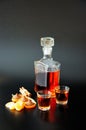 Two glasses and a glass bottle of cognac, chocolates, cinnamon, zest and orange slices Royalty Free Stock Photo