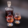 Two glasses and a glass bottle with cognac stands on a black background Royalty Free Stock Photo