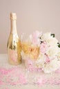 Two glasses, a golden bottle of champagne, a bouquet of roses and pink confetti on the table. Romantic date on Valentine`s Day Royalty Free Stock Photo