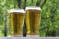 Two glasses of golden cold beer on wooden table, outdoor. With copy space, close up.