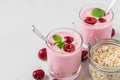 Two glasses of healthy cherry yogurt with fresh berries, oats spoon and mint on white marble table. healthy breakfast