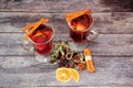 Two glasses of hot red wine with an assortment of spices, cinnamon sticks and orange slices on a wooden table