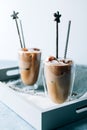 Two glasses of iced cappuccino coffee with ice on grey napkins on wooden tray. Cold brew with milk. Royalty Free Stock Photo