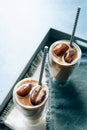 Two glasses of iced cappuccino coffee with ice on grey napkins on wooden tray. Cold brew with milk. Royalty Free Stock Photo