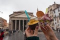 Two glasses of Italian ice cream in the hands of a girl against the Roman Pantheon in Piazza della Rotonda in Italy on a rainy day