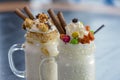 Two glasses or jars of freak shakes on rustic wooden table. Caramel marshmallow candy milk shake cocktail. Royalty Free Stock Photo