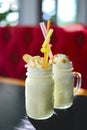 Two glasses or jars of freak shakes on rustic wooden table. Caramel marshmallow candy milk shake cocktail. Royalty Free Stock Photo