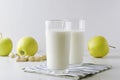 Two glasses of kefir,aplles,nuts,napkin on white table against white background in the kitchen.Concept of milky diet and healthy f